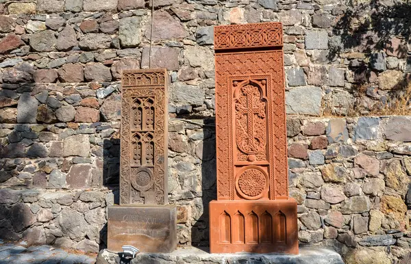 Süslü taş haç haçlarını karmaşık bir şekilde dekoratif desenlerle oyuyor. Yaşlanmış, kayalık arka planda duruyor. Tarihi zanaatkarlık ve kültür mirası sergiliyor. Geghard Ermenistan