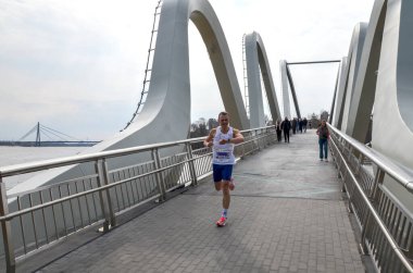 Fütüristik eğri metal dizaynlı, atletik ruhu ve mimari zarafeti simgeleyen önemli bir köprüde yarışan bir adam.