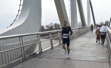 Fütüristik eğri metal dizaynlı, atletik ruhu ve mimari zarafeti simgeleyen önemli bir köprüde yarışan bir adam.