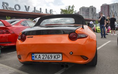 Hafif turuncu, Mazda MX-5, iki kapılı üstü açık, gösterişsiz tasarımı, çevik kullanımı ve zamansız cazibesiyle ünlü.