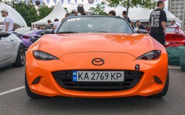Hafif turuncu, Mazda MX-5, iki kapılı üstü açık, gösterişsiz tasarımı, çevik kullanımı ve zamansız cazibesiyle ünlü.