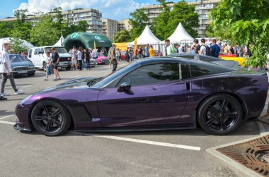 Canlı, mor renkli Chevrolet Corvette. Ön tamponu düşük ve farları parlak ve sembolik tasarımını canlı bir arabada sergiliyor.