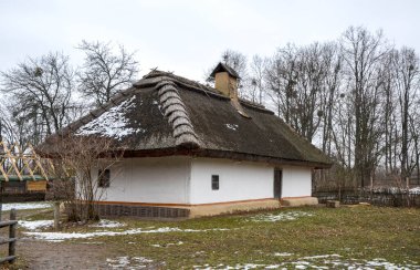 Karlı bir manzarası ve doğal çevre ve ağaçlarla çevrili geleneksel sazdan bir çatısı olan kır evi, eski dünya cazibesi ve dinginliği sergiliyor.
