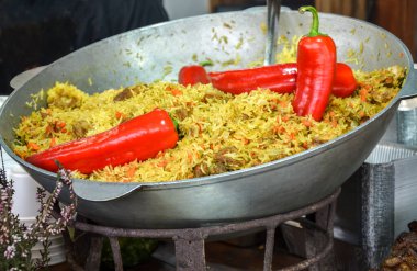 Kırmızı biber ve sebzelerle dolu büyük bir tavada servis edilen enerjik pilav geleneksel yemek pişirme ya da yemek pişirme ya da mutfak fotoğrafçılığının taze malzemelerini sergilemek için mükemmeldi.
