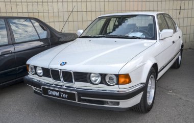 Beyaz BMW 7 Serisi E32, klasik lüks sedan, zamansız tasarımı, gelişmiş teknolojisi ve güçlü motorları var. Alman mühendisliğinin ve idari konforun sembolü