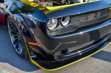 Siyah bir Dodge Challenger 'ın ön tarafında, ızgarasını, farlarını ve sarı aksanlı alt tamponunu vurguluyor.