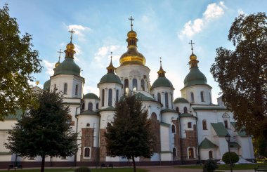 Kyiv St. Sophia Katedrali 'nin haçları olan görkemli altın ve yeşil kubbeler ağaçların çerçevelediği açık mavi gökyüzüne karşı dimdik dururlar.