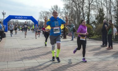 Canlı bir açık hava koşusuna katılan katılımcılar, coşkulu bir seyircinin tezahüratıyla enerji ve kararlılık gösteriyorlar.