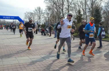 Canlı bir açık hava koşusuna katılan katılımcılar, coşkulu bir seyircinin tezahüratıyla enerji ve kararlılık gösteriyorlar.