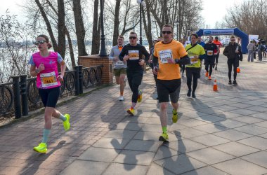 Katılımcılar, berrak bir gökyüzünün altında nehir kenarındaki bir patika boyunca yarışarak enerji ve başarı atmosferi yaratıyorlar.