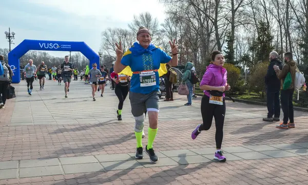 Canlı bir açık hava koşusuna katılan katılımcılar, coşkulu bir seyircinin tezahüratıyla enerji ve kararlılık gösteriyorlar.