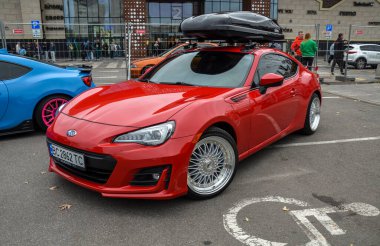 Spor kırmızısı Compact Coupe Subaru BRZ. Piyasa sonrası gümüş alaşımlı tekerleklerle donatılmıştır. Çok dilli tasarımıyla şık ve agresif duruşunu geliştirmiştir.
