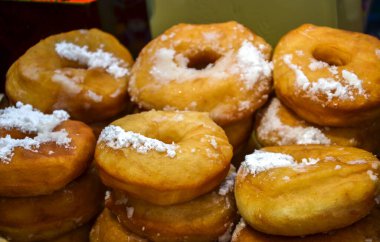 Lezzetli el yapımı çörekler ince pudra şekerle kaplanmış, taze pişmiş mükemmellik ve tatlılık sergileniyor, hamur işi aşıkları cezbediyor.