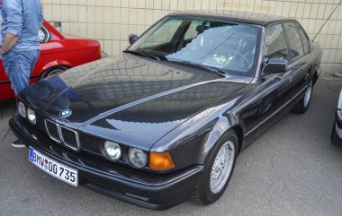 Klasik siyah sedan BMW E32 1990 ileri mühendislik, rafine tasarım ve yüksek performans becerileri ile ünlü otomotiv lüksünde yeni standartlar belirledi