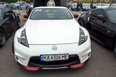 Ön tamponunda kırmızı aksanlı beyaz Nissan 370Z Nismo spor arabası, açık hava otomotiv etkinliğinde sergilenen agresif stil.