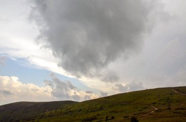 Büyüleyici manzara, yuvarlanan yeşil tepeler dramatik bulutlu gökyüzü ile çelişiyor. Karpat Dağları, Ukrayna