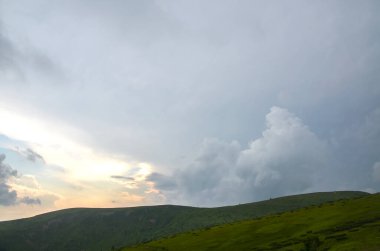 Büyüleyici manzara, yuvarlanan yeşil tepeler dramatik bulutlu gökyüzü ile çelişiyor. Karpat Dağları, Ukrayna