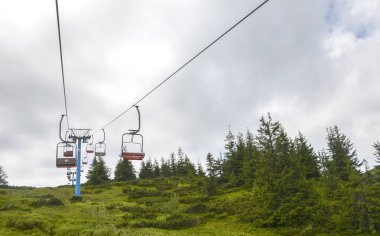 Bereketli yeşil bir manzaranın üzerinde, canlı tepeler, canlı bitki örtüsü ve sakin bir çevreye sahip, açık hava keşiflerini, doğayı ve rahatlamayı sembolize ediyor.