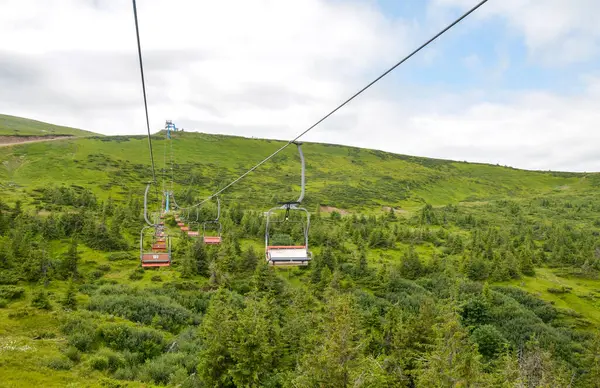 Bereketli yeşil bir manzaranın üzerinde, canlı tepeler, canlı bitki örtüsü ve sakin bir çevreye sahip, açık hava keşiflerini, doğayı ve rahatlamayı sembolize ediyor.