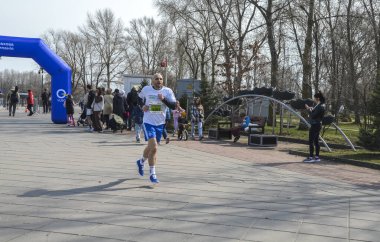 Bir maratonu tamamlayan kararlı bir sporcu, açık gökyüzünün altındaki bir açık hava etkinliğine katılıyor.