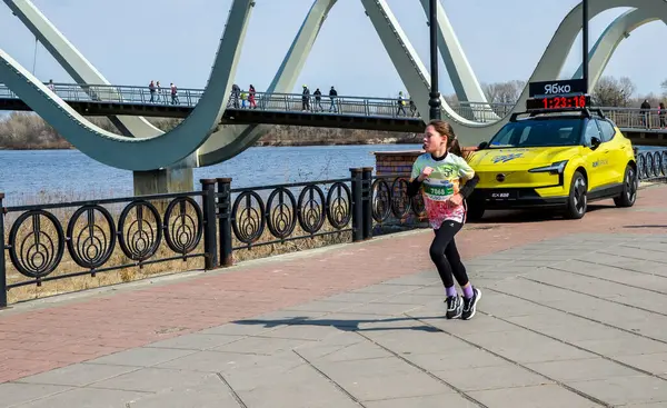 Kentsel bir çevrede düzenlenen bir spor etkinliği sırasında nehir kenarında koşan genç bir sporcu kız.