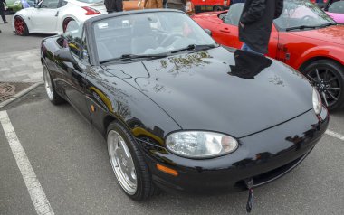Siyah Mazda MX-5 Miata üstü açık araba fuarında gösterişli tasarımını sergiliyor. Otomotiv özellikleri, klasik araba galerileri veya etkinlik promosyonları için mükemmel.