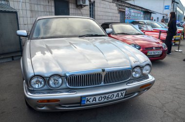 Klasik Jaguar XJ (X308) gümüş renginde, açık havada park edilmiş. Zarif kıvrımlı, krom aksanlı ve zamansız rafine edilmiş ikonik İngiliz lüks sedanı.