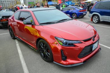 Spor Toyota Scion TC açık havada park edilmiş, şık çizgiler sergileniyor ve modern bir coupe tasarımı var. Şık ve pratik ön ızgarası olan kompakt bir araba.
