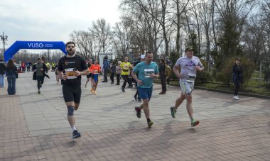 Maraton katılımcıları bir park yolu boyunca koşuyor, atletik dayanıklılık, kararlılık ve açık hava aktivitesi sergiliyorlar.