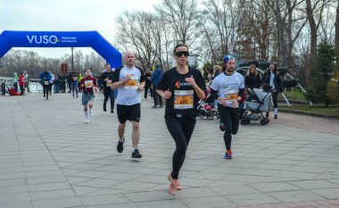 Maraton katılımcıları bir park yolu boyunca koşuyor, atletik dayanıklılık, kararlılık ve açık hava aktivitesi sergiliyorlar.