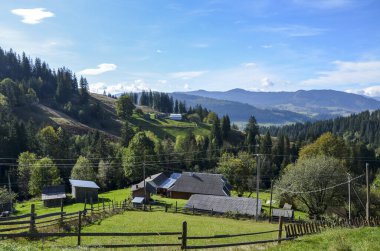 Dağ köyünün sakin kırsal manzarası. Parlak mavi gökyüzünün altındaki yemyeşil alanlar ve ormanlarla çevrili. Doğal ve barışçıl ortamda kırsal yaşamın güzelliğini gözler önüne seriyor. Karpatlar, Ukrayna