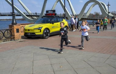 Köprünün yakınındaki bir maratona katılan bir grup çocuk ve nehir kenarındaki güzel bir parkta eğlenen seyirciler.