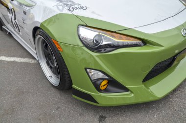 Beyaz ve limon yeşili Scion FR-S spor arabasının ön çeyreğini yakalıyor. Özel boya işi, satış sonrası tekerlekleri ve sarı sis ışığı.
