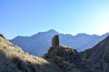 Yalnız, yıpranmış bir taş kule, yüksek dağlar ve engin mavi gökyüzü tarafından çerçevelenmiş bir tepenin üzerinde duruyor, antik çağın ve engebeli yabanın bir duygusunu çağrıştırıyor. Stepantsminda, Georgia