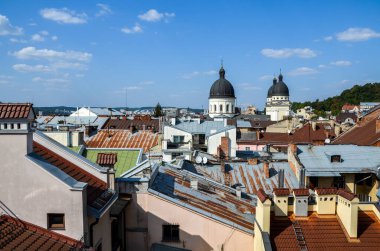 Lviv 'in çatılarının panoramik görüntüsü, belirgin şekil değiştirme kilise kubbelerinin hakim olduğu çeşitli doku ve renklerle berrak mavi gökyüzüne karşı.