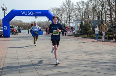 Rekabetçi koşucular, pitoresk bir parktaki koşu müsabakasına katılıyor, sportmenlik, fitness ve coşku gösterisi yapıyorlar.