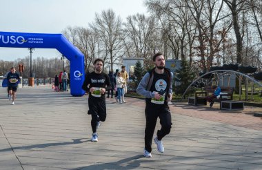Rekabetçi koşucular, pitoresk bir parktaki koşu müsabakasına katılıyor, sportmenlik, fitness ve coşku gösterisi yapıyorlar.