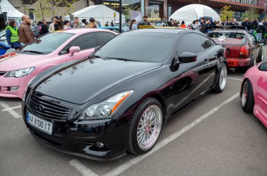 Parlak siyah Infiniti Q60 coupe, özelleştirilmiş lüks spor araba açık hava otomobil fuarında sergileniyor. Modifiye lüks araçlar, araba fuarı atmosferleri ve özel araba kültürü