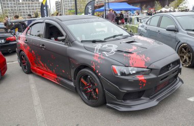 Matte black Mitsubishi Lancer Evolution ve agresif kırmızı sıçrama grafikleri. Özel yapım siyah ve kırmızı tekerlekler, geniş vücut kiti ve spoiler içerir.
