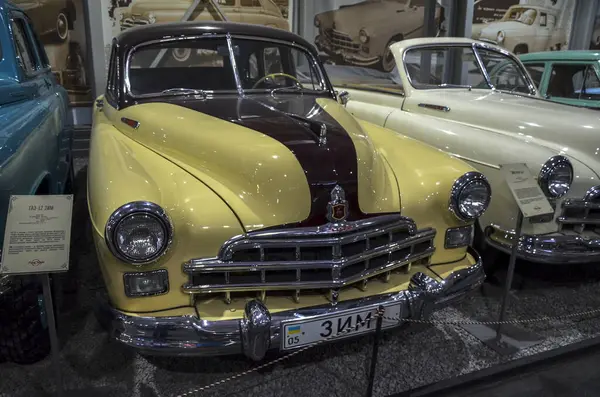 Çarpıcı iki tonlu klasik araba, GAZ-12 ZIM, krem gövde ve koyu bordo kaplama çizgili, belirgin krom ızgara ve tampon, kapalı alanda sergileniyor.