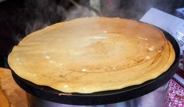 Isıtılmış ızgarada pişen sıcak altın krep görünür bir buharla taze bir hazırlık sergiliyor.