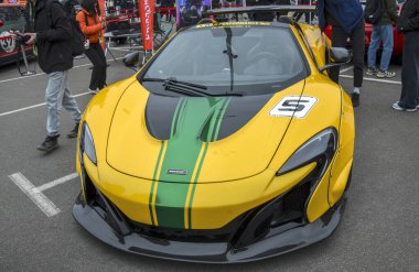 Canlı sarı McLaren 650S Örümcek Özgürlük Yürüyüşü yeşil yarış çizgileri ve büyük bir arka kanat açık hava araba fuarında park halinde.
