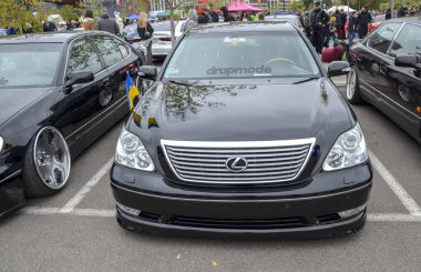 Parlak siyah Lexus LS lüks sedan. Özel tekerli ve özel süspansiyonlu. Bir açık hava otomotiv etkinliğinde VIP tarzı modifikasyonlar.