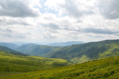 Bulutlarla dolu dramatik bir gökyüzünün altındaki yemyeşil tepeler doğanın en saf haliyle dingin güzelliğini yakalıyor. Svydovets, Karpatlar, Ukrayna