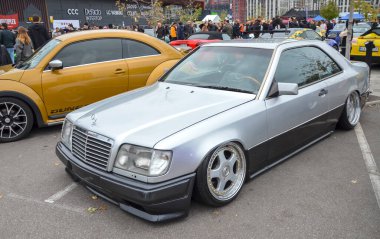 Gümüş rengi Mercedes-Benz E-Sınıfı W124 sedan, sağlam yapım kalitesi, konforlu sürüş ve geniş motor yelpazesi ile ünlü klasik bir yönetici arabası.