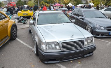 Gümüş rengi Mercedes-Benz E-Sınıfı W124 sedan, sağlam yapım kalitesi, konforlu sürüş ve geniş motor yelpazesi ile ünlü klasik bir yönetici arabası.
