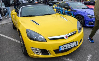 Açık sarı Satürn Gökyüzü üstü açık parlak, iki koltuklu bir araç. Saldırgan ön bağları ve öne çıkan başlık delikleri ona sportif bir görünüm kazandırıyor.