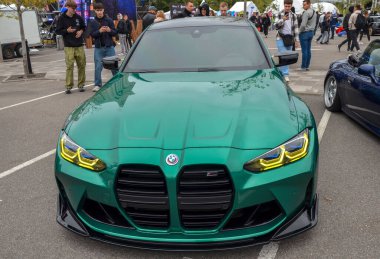 Çarpıcı yüksek performanslı BMW M3 (G80) sedan, geniş dikey böbrek ızgarası ve agresif ön fasya ile eşsiz metalik yeşil boya ile tamamlanmış.