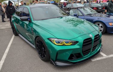 Çarpıcı yüksek performanslı BMW M3 (G80) sedan, geniş dikey böbrek ızgarası ve agresif ön fasya ile eşsiz metalik yeşil boya ile tamamlanmış.