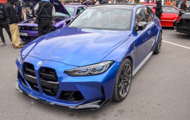 Canlı mavi BMW M3 yarışma sedanı belirgin büyük dikey böbrek ızgarası, agresif ön ayırıcı ve siyah aerodinamik elementlere sahiptir.